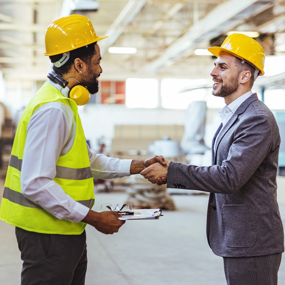 two men with hardhats and protective vests speaking